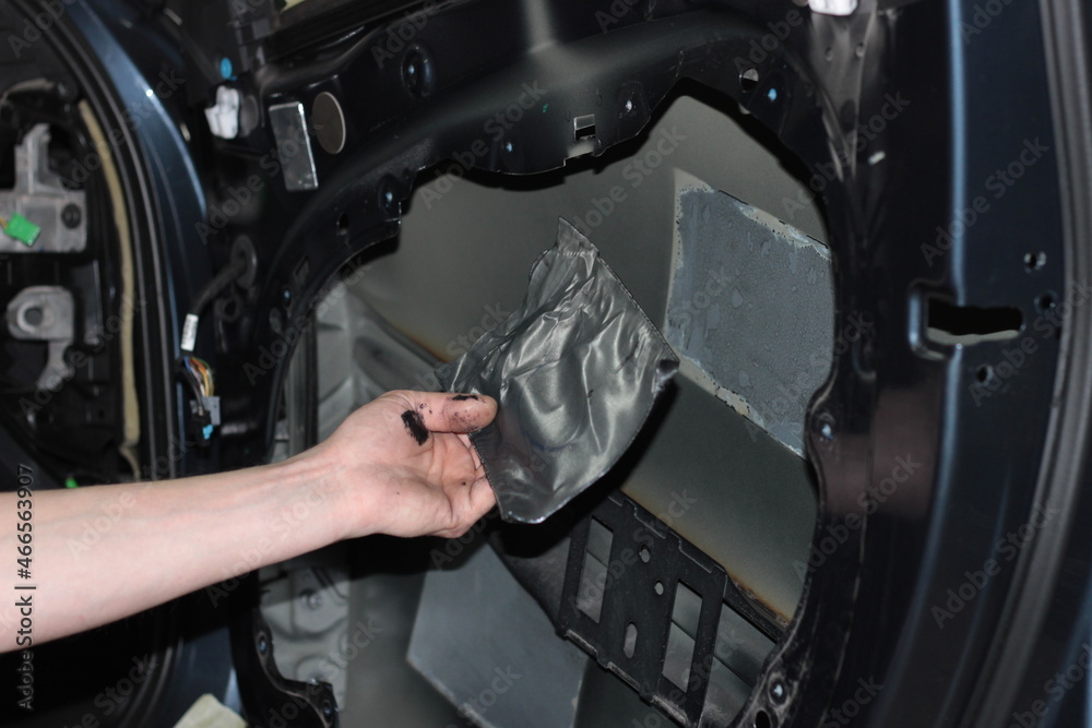 Car tuning. The man removes the vibration isolation from the car door