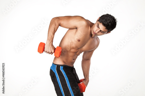 Side view portrait of strong handsome shirtless sportsman training his triceps, having workout for arms, has concentrated expression. Indoor studio shot isolated on white background.