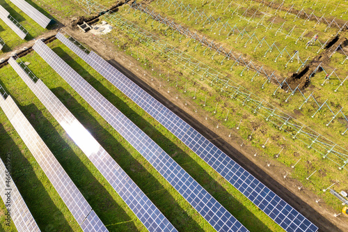 Aerial view of solar power plant under construction on green field. Assembling of electric panels for producing clean ecologic energy.