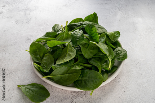 Fresh spinach leaves in a bowl on gray background. Healthy food ingredient