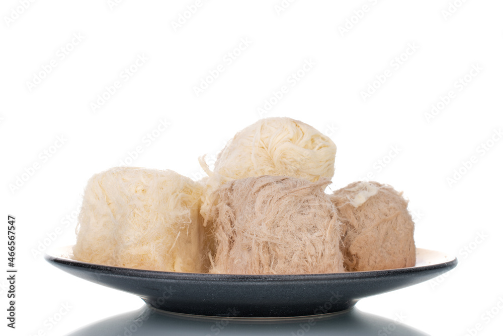 Several sweet cotton candy on a ceramic plate, close-up, isolated on white.
