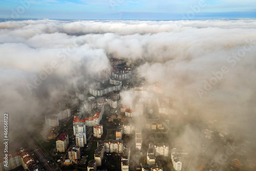 Top aerial view of fluffy white clouds over modern city with high rise buildings.