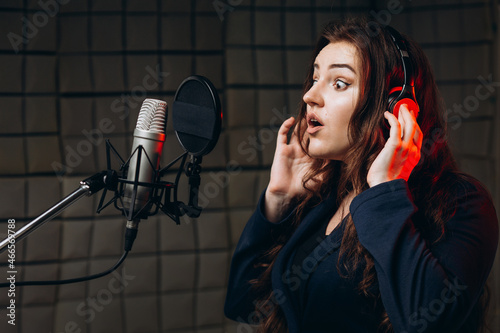 Female with microphone recording a voice for dubbing in music studio