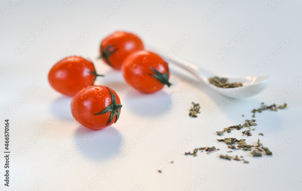 red cherry tomatoes and white spoon on a white background red cherry tomatoes and white spoon on a white background