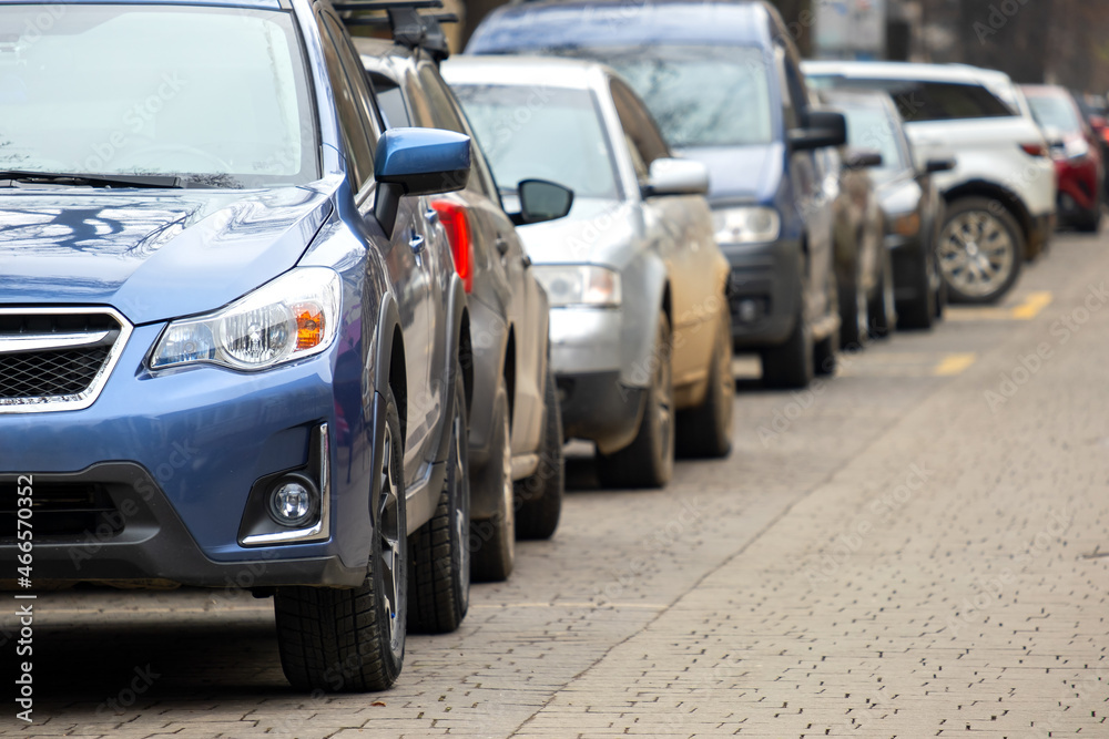 Cars parked in a row on a city street side. Cars parked in a row on a city street side.