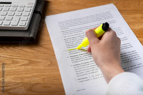 Contract terms of contract. Hand highlighting word in legal agreement, studying and reading business document.