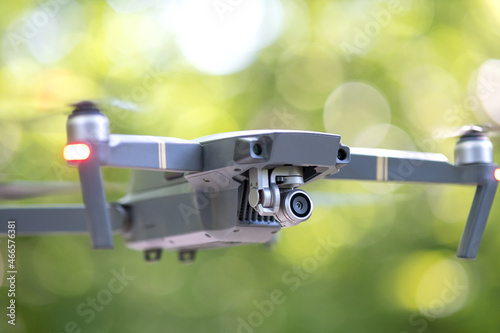 Drone aircraft with blurred fast rotating propellers and photo camera flying in air.