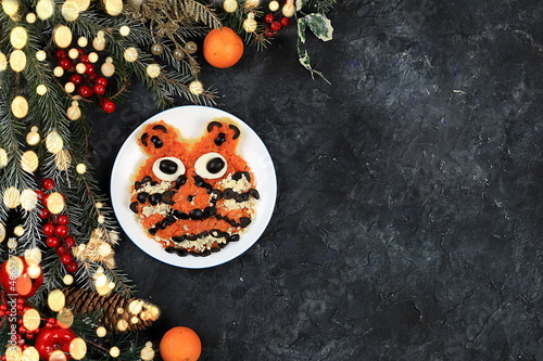 Christmas new year dishes, traditional festive tiger cub salad, symbol of the year made of carrots, olives, cheese for vegan food, fir branches and cones and decorations, food design idea, 