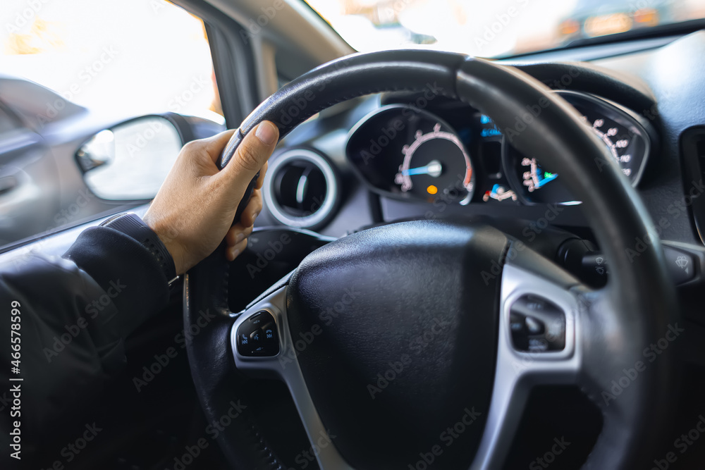 close-up of a man's hand holding the steering wheel of a car.