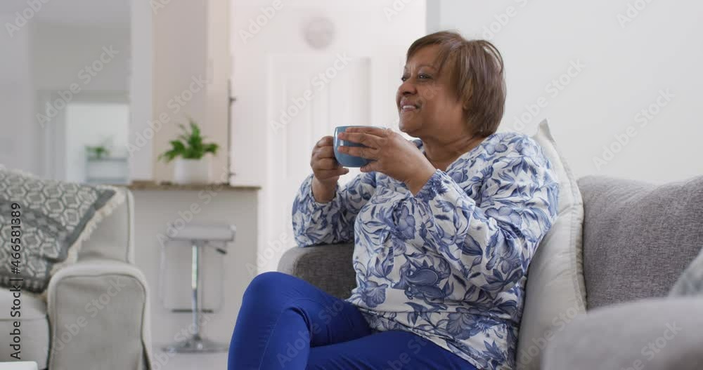 Happy african american senior woman in living room drinking cup of tea, looking away smiling Happy african american senior woman in living room drinking cup of tea, looking away smiling