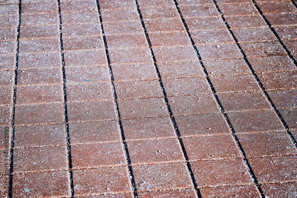 Rock salt crystals (sodium chloride) on paving slabs and asphalt roads