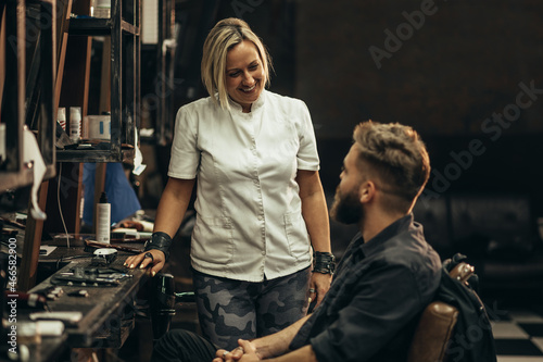 Man getting talking with his hairdresser while sitting in chair at barbershop