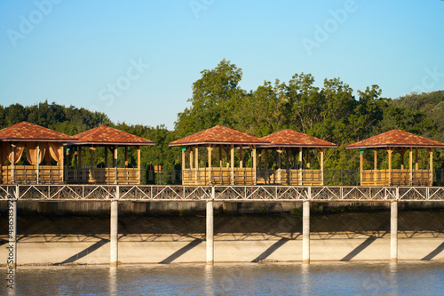 The embankment on round reinforced concrete piles is raised above the shore of the reservoir. On the embankment there are wooden gazebos for relaxation.