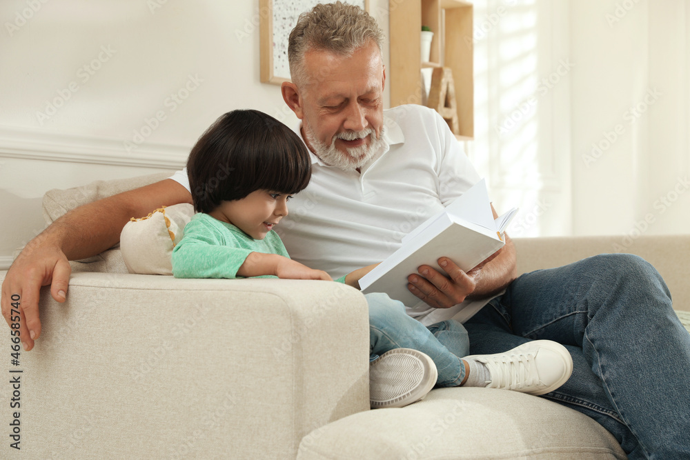 Happy grandfather with his grandson reading book together at home Happy grandfather with his grandson reading book together at home