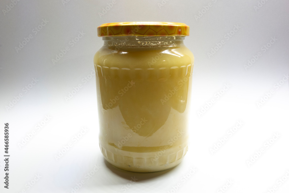 Fresh honey from bee plastic in a glass bottle with a cap on a light background. Fresh honey from bee plastic in a glass bottle with a cap on a light background.