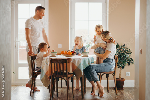a young family has breakfast on a weekend at home in the kitchen together 