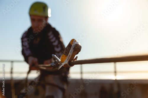 Industrial climber in a helmet pulls a rope on the roof of a building. Blurred background, background image photo