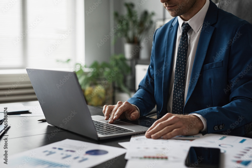 Cropped shot of successful businessman in suit working at able in office and using laptop, copy space - obrazy, fototapety, plakaty 