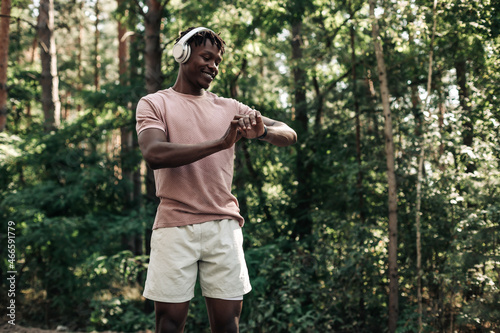 Male runner, American man checking fitness progress on his smartwatch while walking in the woods in nature
