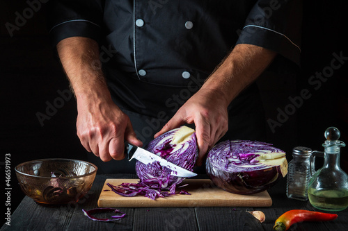 The chef is cutting red cabbage with a knife. Cooking vegetable salad in the restaurant kitchen. Vegetable diet idea