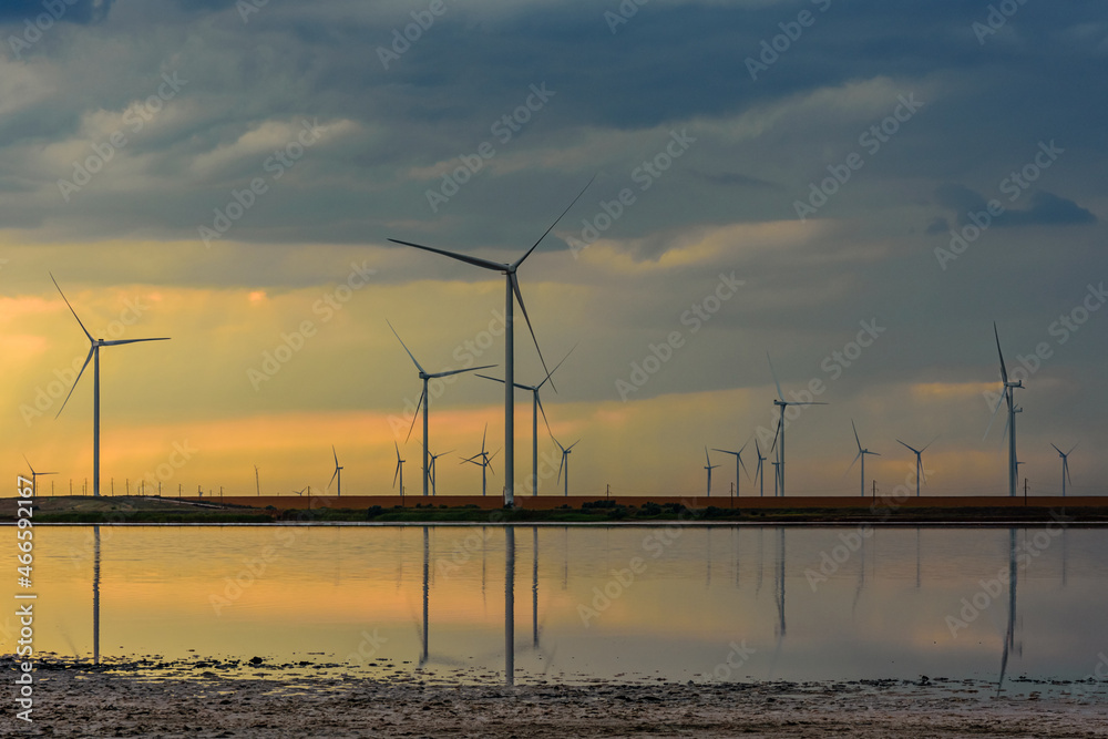 Wind turbines at the shore of Lemurian lake at sunset. Clean energy. Ecological concept