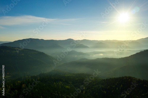 Sun shining over forest in misty mountains. Drone photography