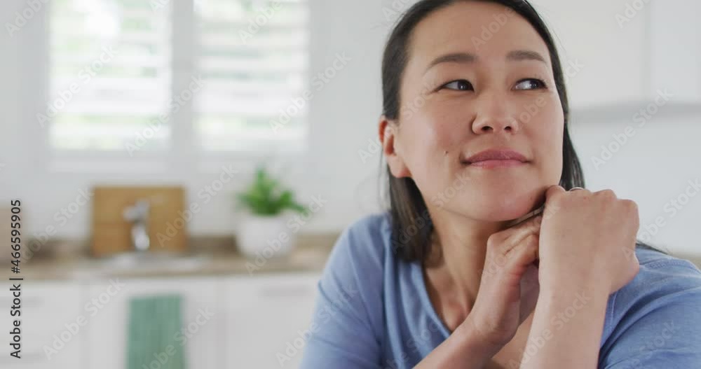 Portrait of happy asian woman sitting in kitchen Portrait of happy asian woman sitting in kitchen