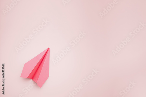 airplane made with pink colored paper on light yellow color