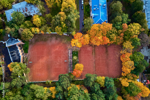 Aerial view of a tennis court surrounded by beautiful trees in autumn