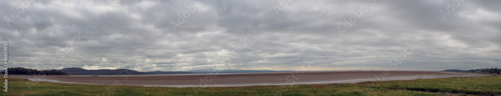 panoramic view of the coast at grange over sands in cumbria with grass covered wetland in the foregrounds and the north lakes area in the distance
