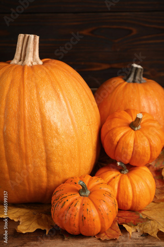 Pile of ripe pumpkins and dry leaves on wooden table