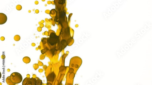 Chamomile oil is poured into the water creating a lot of different sized clear yellow bubbles on white background | Abstract body care cosmetics with chamomile oil formulation concept photo