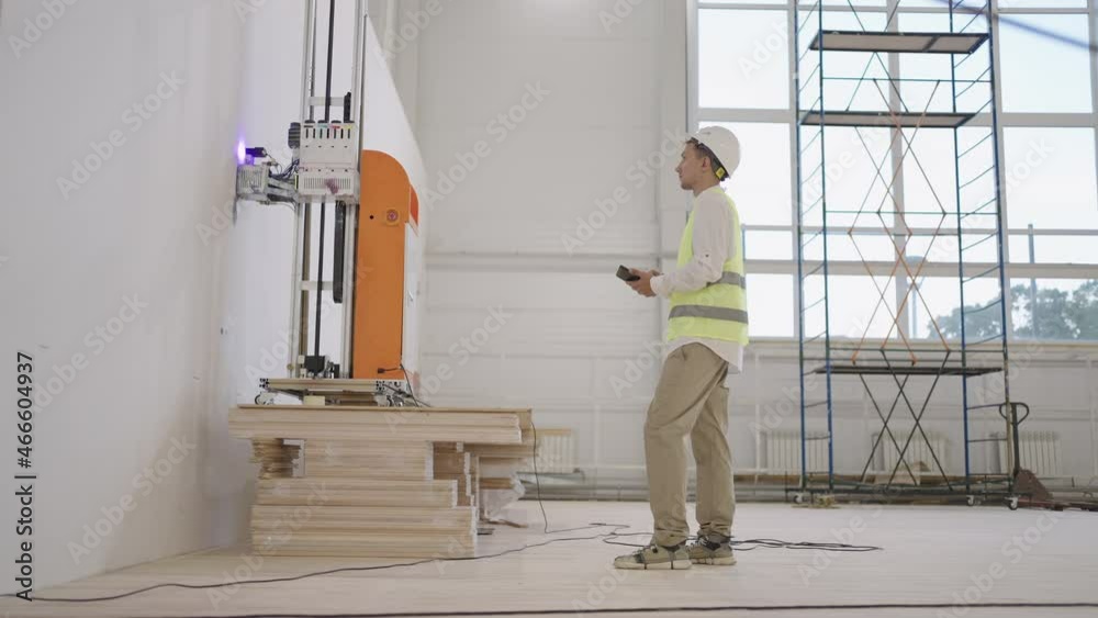 A software engineer adjusts the operation of the robot for laser printing on the wall. Printing on walls in industry A software engineer adjusts the operation of the robot for laser printing on the wall. Printing on walls in industry