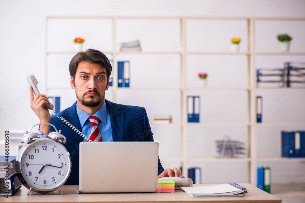 Young male employee in time management concept Young male employee in time management concept