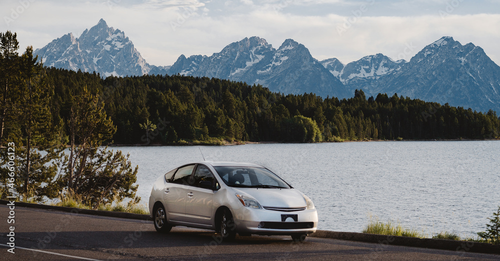 a car parked in front of a lake and mountains