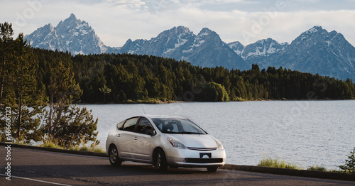 a car parked in front of a lake and mountains