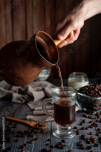 coffee in fresh beans with cup of coffee and old coffee pot with dark wooden background and dark style sugar bowl