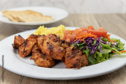 Tikka chicken grilled to perfection served with rice, salad, and pita flat bread for a hearty Mediterranean meal