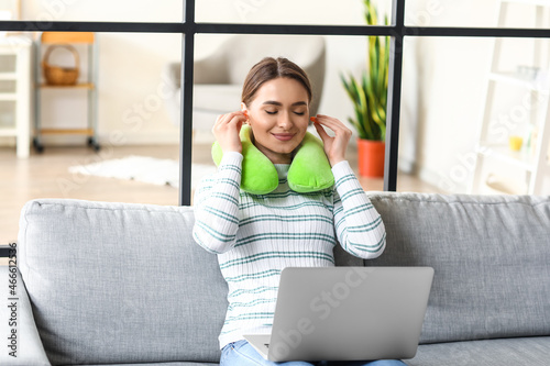 Young woman with earplugs and laptop resting at home photo