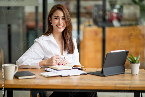 Shot of an Asian young businesswoman working on a laptop computer in her workstation.Portrait of Business people employee freelance online marketing e-commerce telemarketing concept.