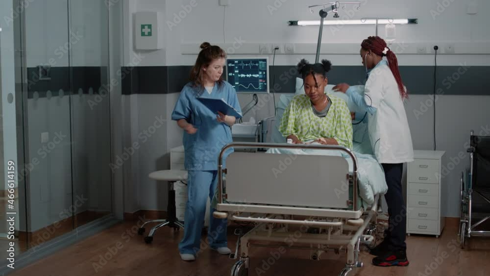Woman working as medic doing consultation with stethoscope in bed. Medical physician examining heartbeat and pulse of woman with sickness while nurse giving assistance to doctor. Woman working as medic doing consultation with stethoscope in bed. Medical physician examining heartbeat and pulse of woman with sickness while nurse giving assistance to doctor.