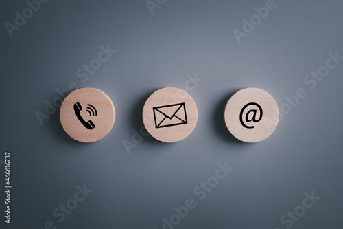 E-mail address ,telephone number and letter icons print screen on circle wooden block on table for webpage business contact and customer service concept..