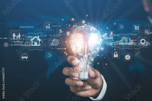 Businessman holding a light bulb showing imaginary graphics of business network technology innovation. 