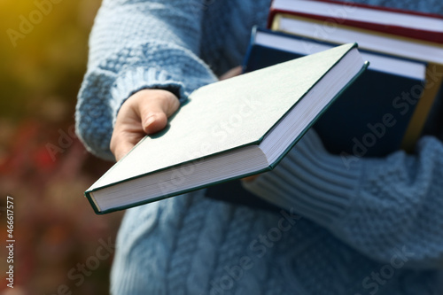 Woman with books in autumn park, closeup