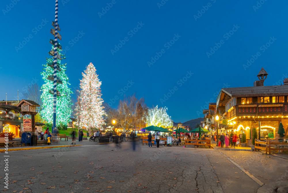 Evening view of the Bavarian themed village of Leavenworth, Washington, USA, with holiday lights illuminating the outdoor cafes and shops.