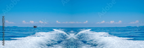 Water splash behind the ship or wake of speed boat in the ocean with beautiful blue sky and white clouds use for holiday and transportation background