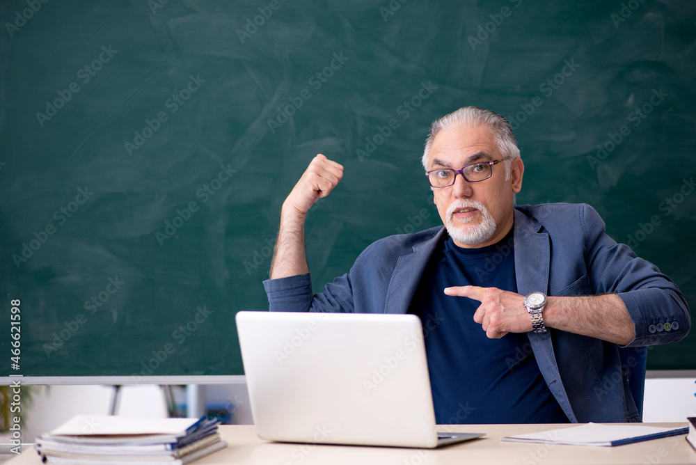 Old male teacher in the classroom Old male teacher in the classroom