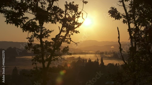 camera pan of sunrise over misty farm valley photo