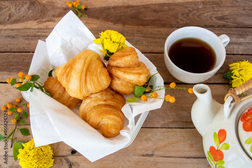 croissant dessert snack on paper with hot tea arrangement flat lay style on background wooden