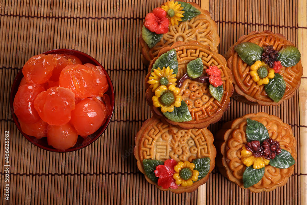 Mid autumn festive colorful flower decorated moon cake making ingredients salted egg yolk cut slice on blue ceramic plate background on bamboo food mat